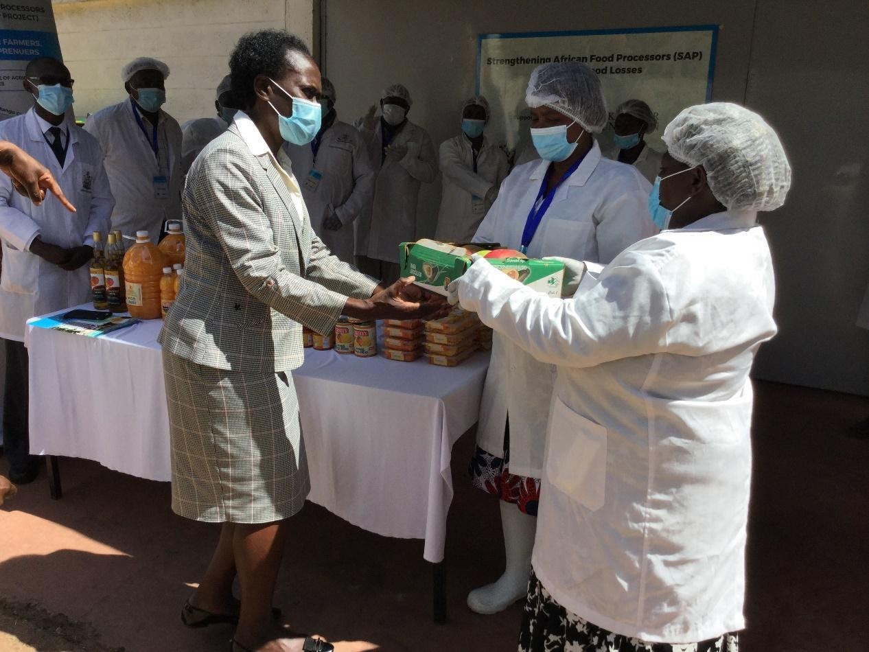 The Principal, Prof. Rose Nyikal receives a gift of fresh mango fruits from the Kawala Group leader, Mrs Teresia Benjamin